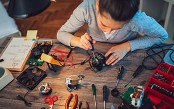 Girl constructs robotic toy. Robotic toy on a wood table full of tools
